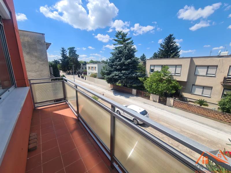 A balcony on a family house in Nové Zámky with a view of a quiet street and greenery.