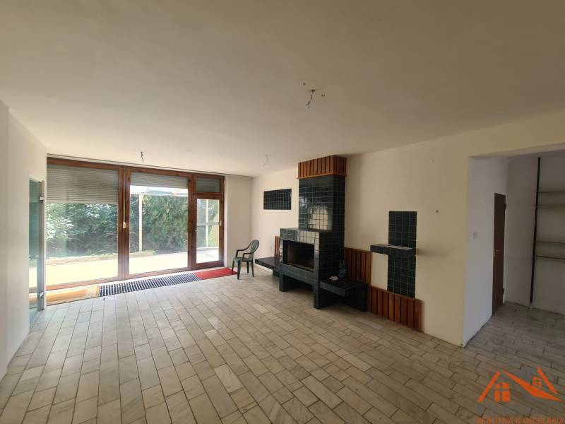 Fireplace in a family house with large windows and tiles, seating area.
