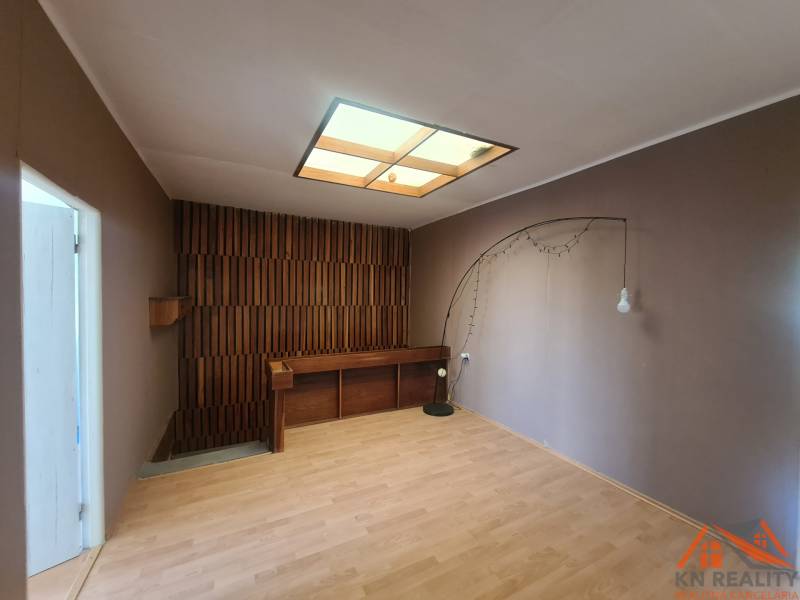 A room in a family house with wooden panels and flooring, lighting with a decorative element.