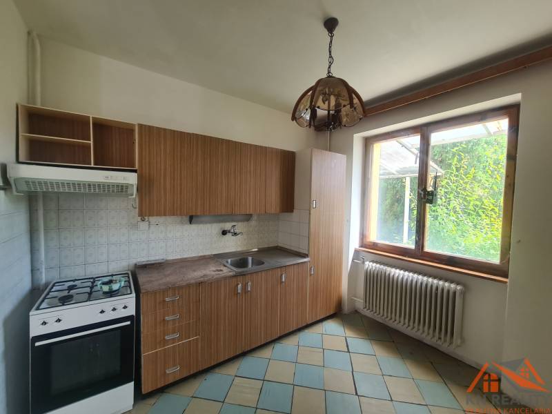 A kitchen with wooden cabinets in a family house, large window, gas stove.