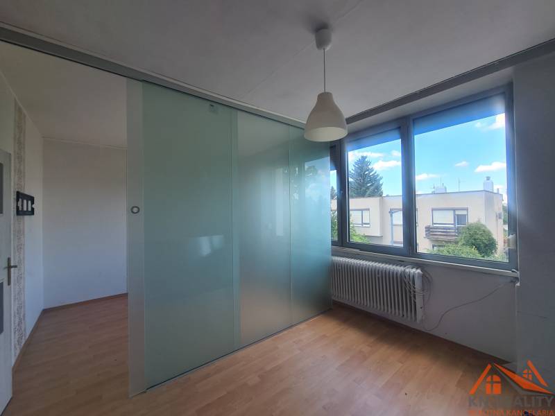Interior of a family house with a glass partition, wooden floor, and large windows.