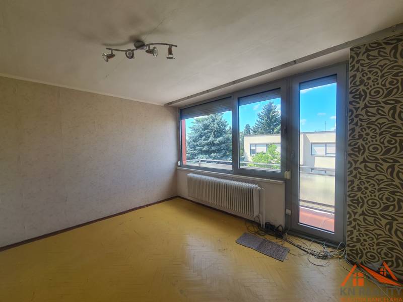 A room with a yellow floor, large windows, and a patterned wall in a family house.