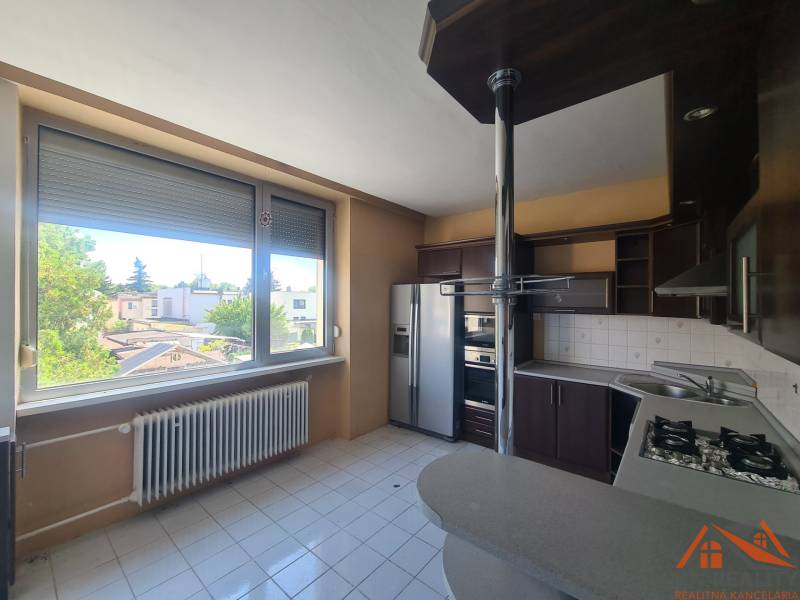 A kitchen in a family house with a view of the garden, equipped with appliances and large windows.