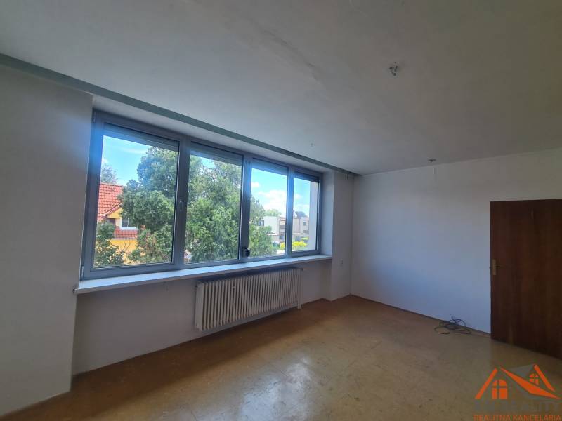 An empty room with a large window, wooden door, and radiator in a family house.