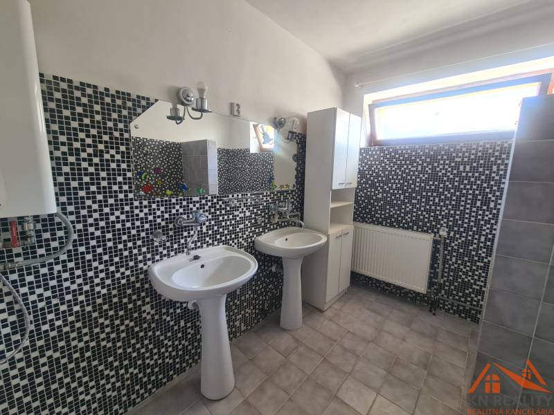 A bathroom with two sinks and mosaic tiles in a family house.