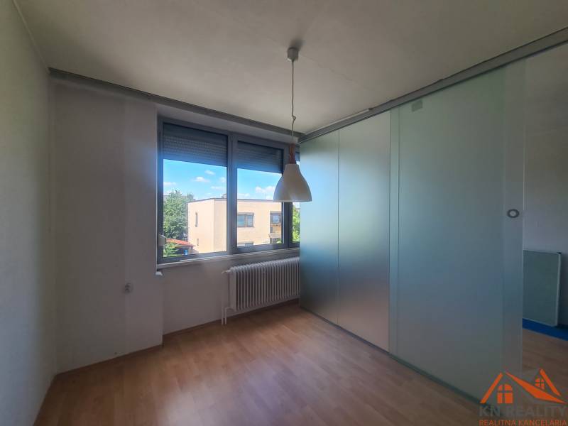 Interior of a family house with laminate flooring, a radiator, and sliding glass doors.