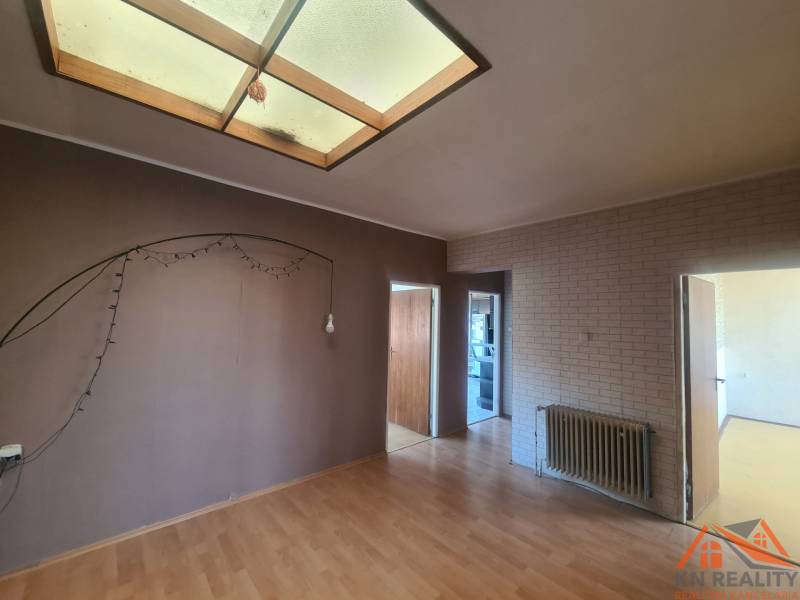 Interior of a family house with an empty room, parquet floor, and brick wall.