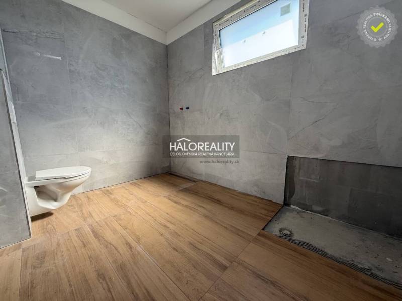 A bathroom in a family house with tiles and a free-standing toilet, waiting to be finished.