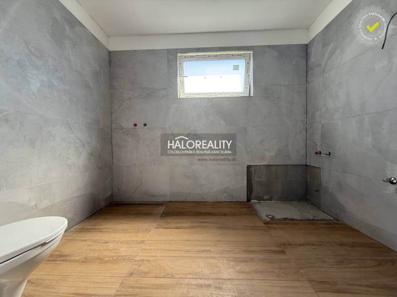 A bathroom in a family house with a white toilet and gray tiles.