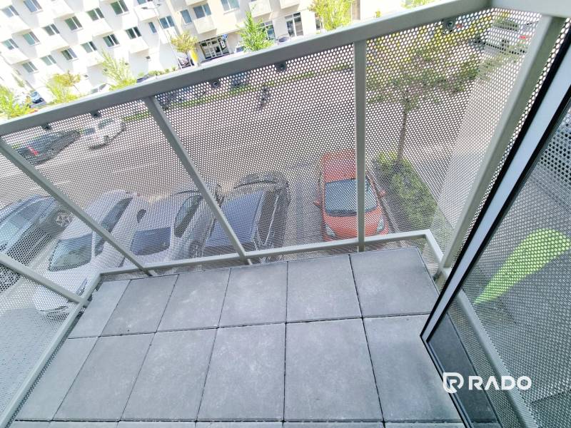A balcony with a view of the parking lot and trees from a 3-room apartment.