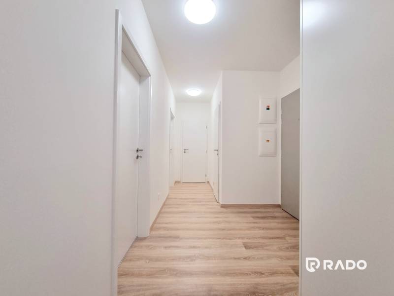 A hallway equipped with lights in a 3-room apartment with white doors and wooden flooring.