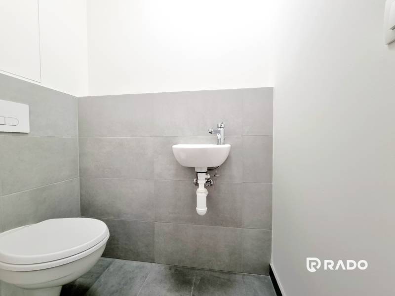 Gray bathroom with a wall-mounted toilet and sink in a 3-room apartment.
