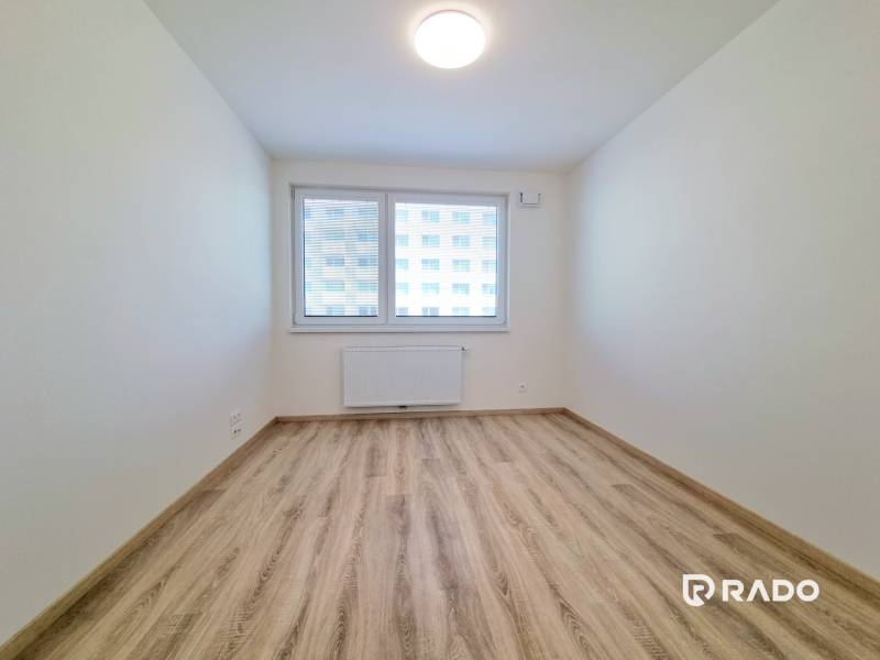 A room in a 3-room apartment with laminate flooring and a window with a view.