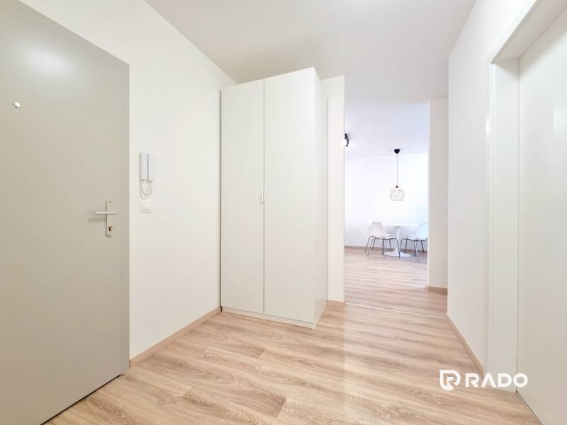A bright hallway with wooden flooring and white furniture in a 3-room apartment.