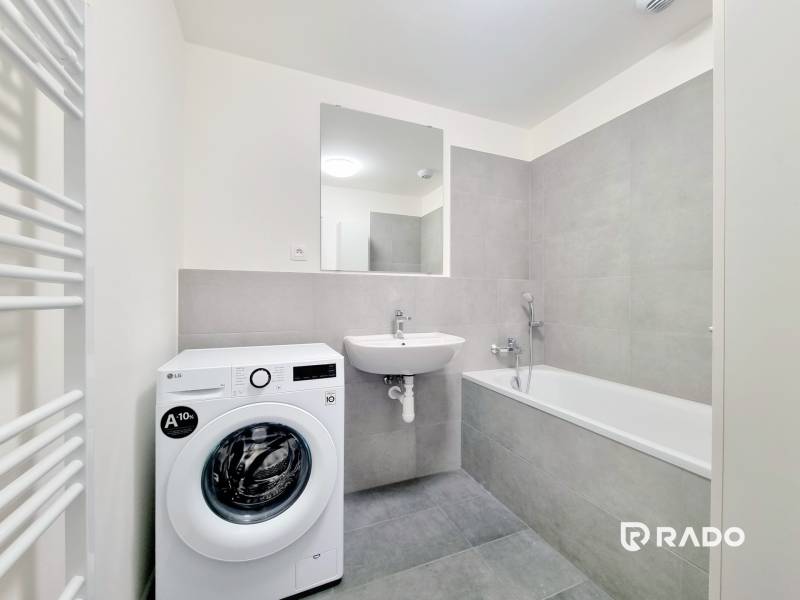 Bathroom in a 3-room apartment with a bathtub, washing machine, and sink.