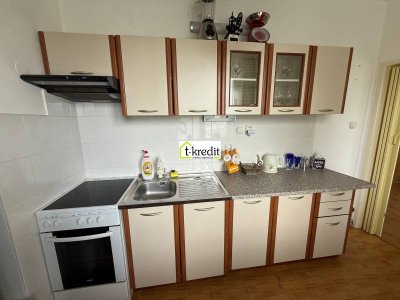 A kitchen in a 2-room apartment with white cabinets and a stove with a hood.