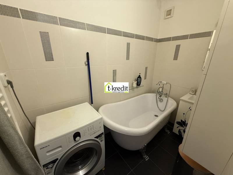 A bathroom in a 2-room apartment with a freestanding bathtub and a washing machine.