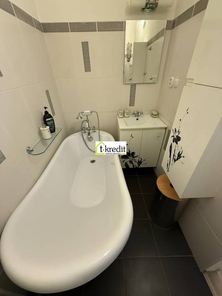 Bathtub in the bathroom with a shower faucet and a sink in a 2-room apartment.