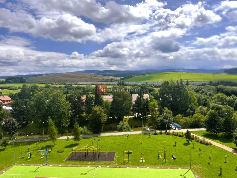 View from a 2-room apartment in the West of Tvrdošín, with a playground and hilly landscape.
