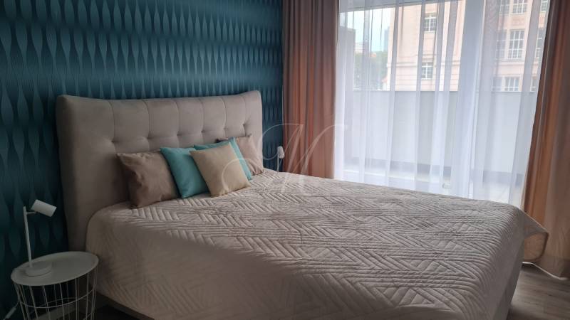 A bedroom with a bed and decorative pillows in a 2-room apartment.