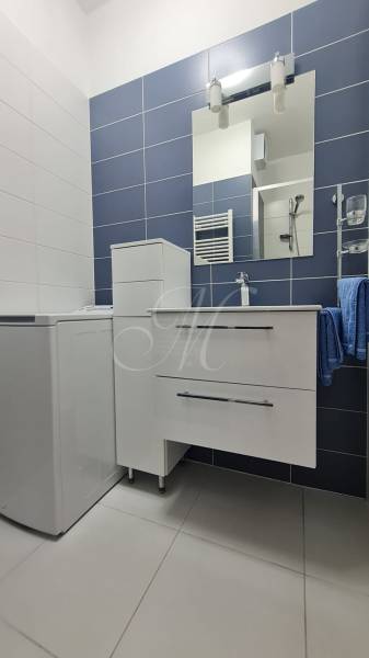 Bathroom in a 2-room apartment with a cabinet, sink, and mirror on the wall.
