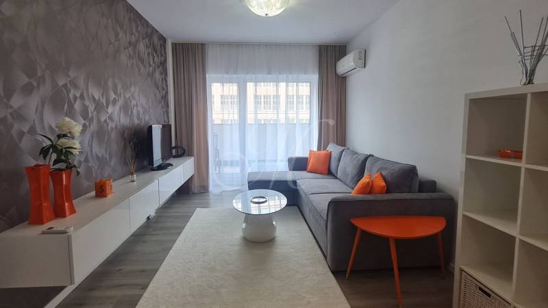 Living room with a sofa, television, and orange decorations in a two-room apartment.