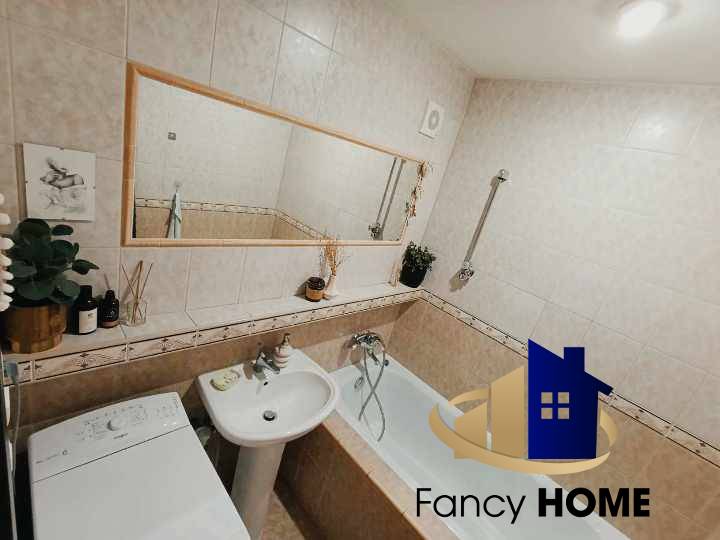 Bathroom with a bathtub and a washing machine in a 3-room apartment, subtle decorations and a mirror.