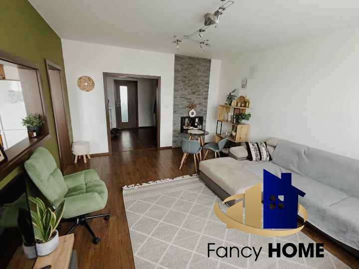 Living room with a brown floor and a gray sofa in a three-room apartment.