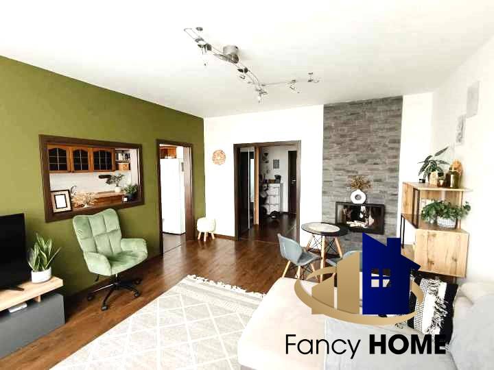 Living room with wooden flooring and a green wall in a three-room apartment.