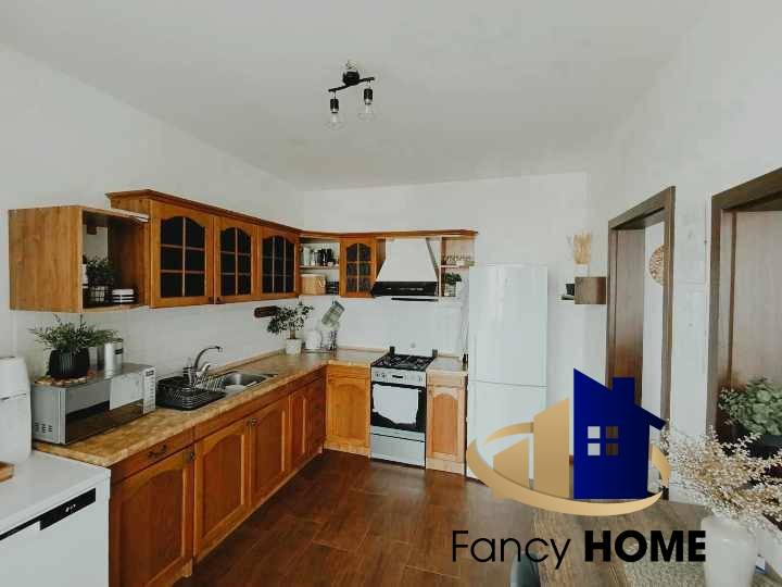 A kitchen in a 3-room apartment with wooden cabinets, a white refrigerator, and a stove.