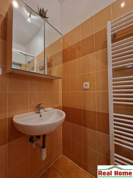 A bathroom in a studio apartment with a mirror and a sink, tiled.