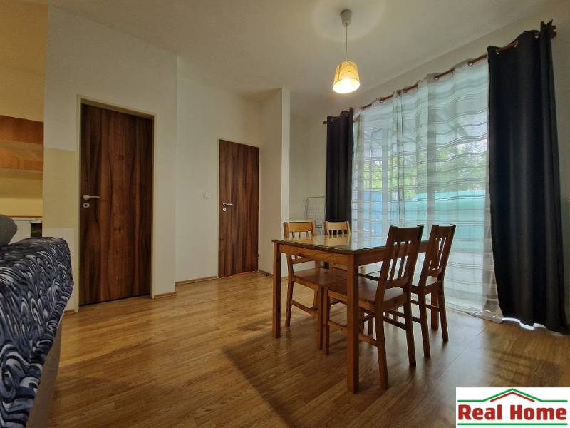 Dining room in a one-room apartment with wooden furniture and glass doors.