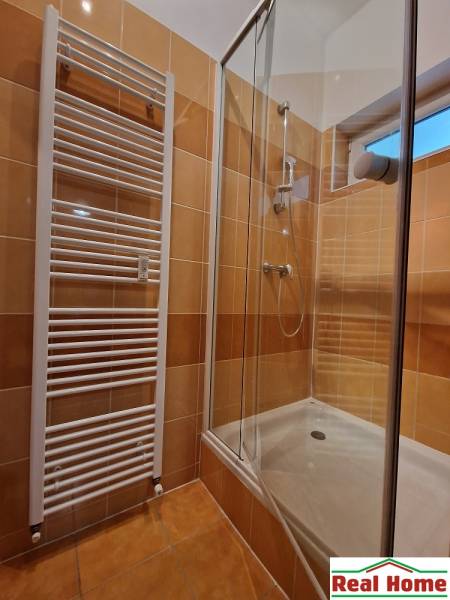 Shower corner in the bathroom of a one-room apartment with tiles and a radiator.
