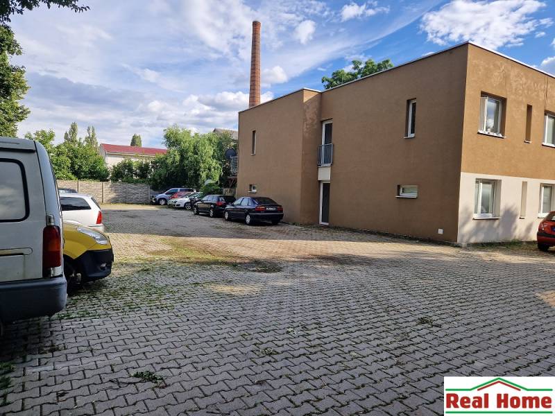 Parking lot on Tehelná Street in Pezinok with cars and a building, place for a 1-room apartment.
