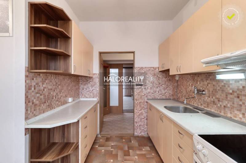 A kitchen in a 3-room apartment with wooden cabinets and tiled backsplash.