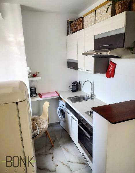 A kitchen in a 2-room apartment with a refrigerator, dishwasher, cabinets, and appliances.