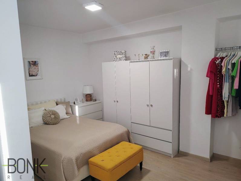 A bright bedroom in a 2-room apartment with a wardrobe, bed, and colorful furniture.