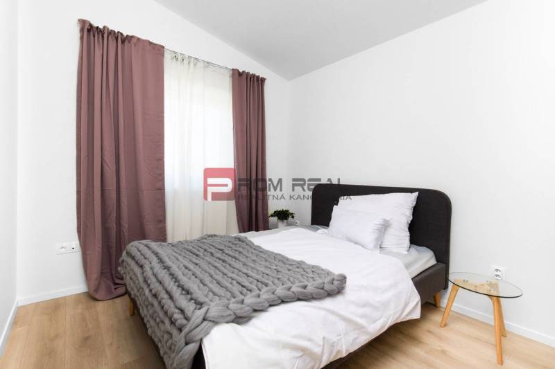 Bedroom in a 3-room apartment with a bed, gray blanket, and nightstand.