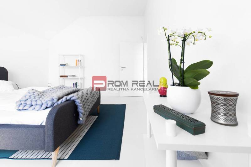 A bedroom with a bed, white furniture, and decorations in a three-room apartment.