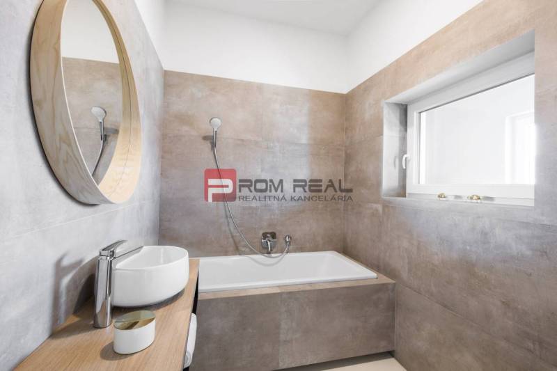 A bathroom with a bathtub and a sink in a 3-room apartment, simplicity and light tones.
