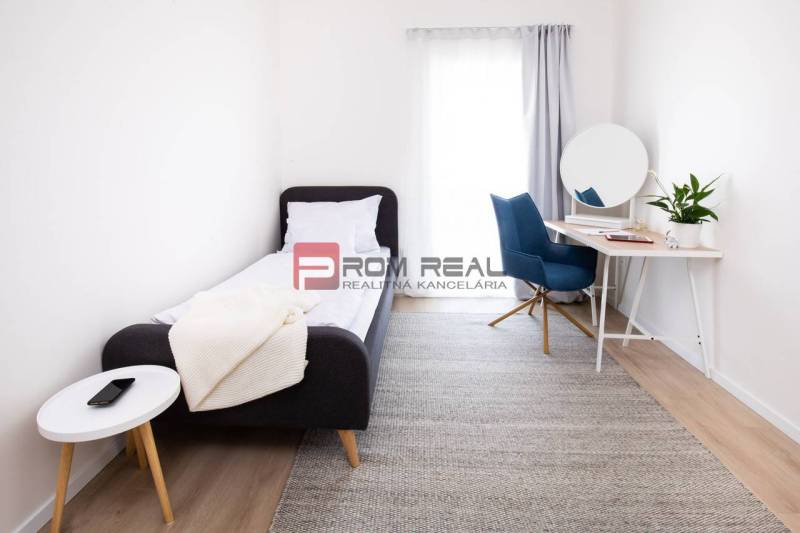 A simple room in a 3-room apartment with a bed, desk, and decorations.