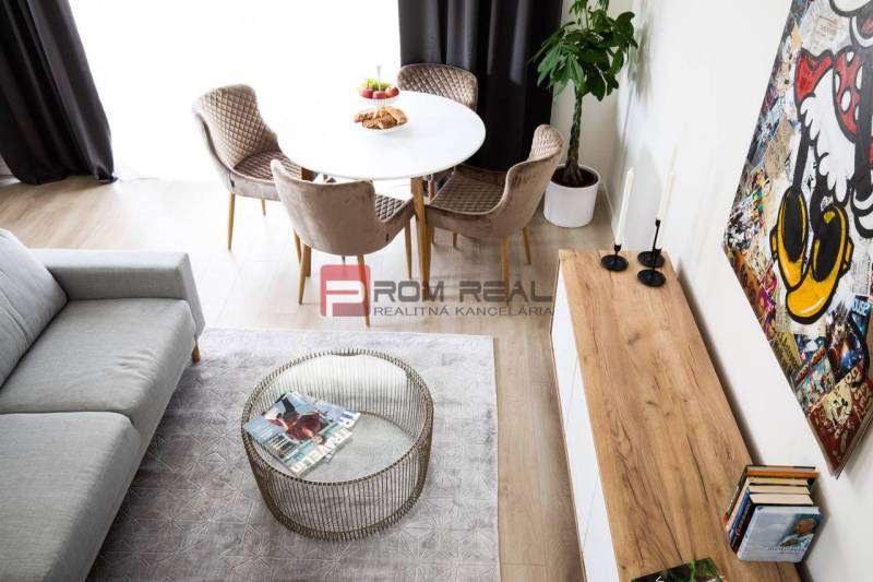 Dining area in a 3-room apartment with a round table, sofa, and carpet.