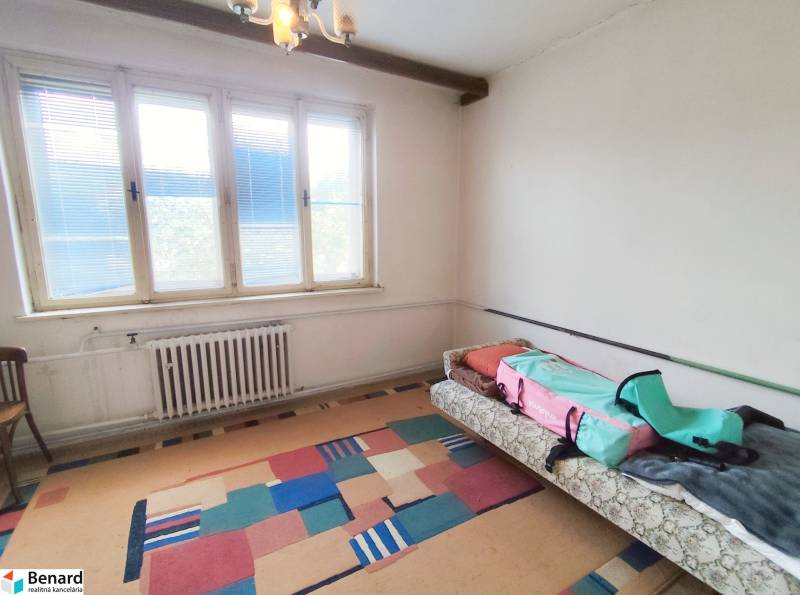 A room in a family house with a large window, carpet, sofa bed, chair.