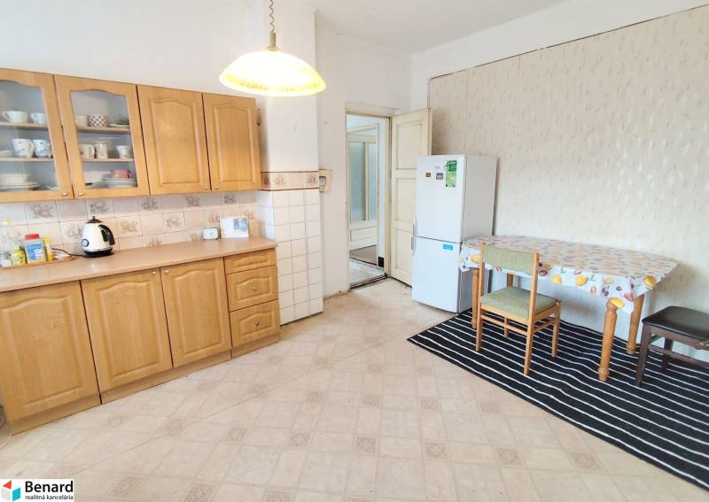 A kitchen in a family house with a wooden cabinet, table, and refrigerator.