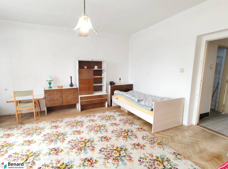 A room in a family house with antique furniture, a carpet, and a bed.
