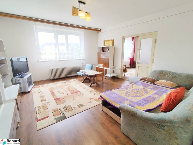 Living room in a family house with a TV, sofa, and wooden table on a carpet.