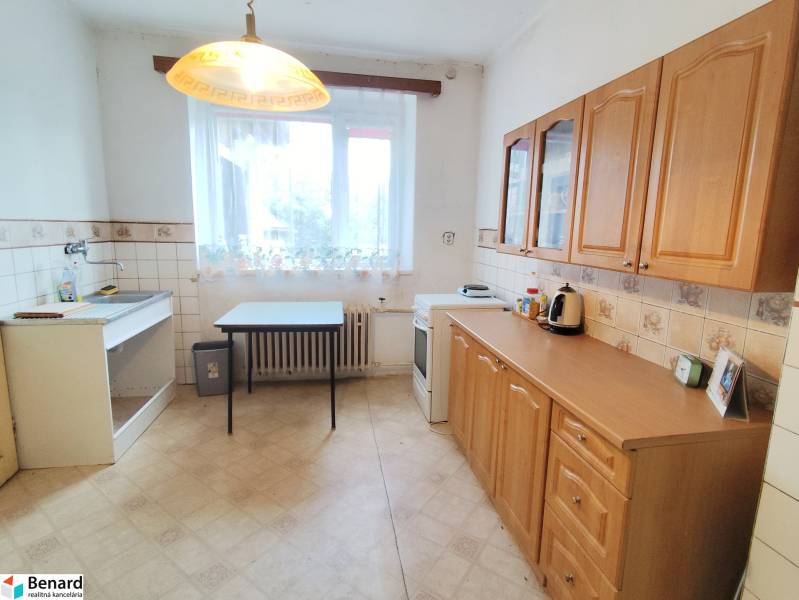 A kitchen in a family house with a wooden kitchen unit and a window without curtains.