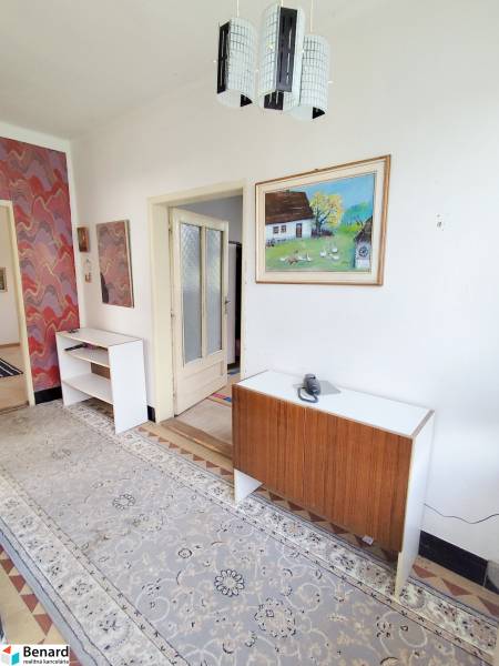 A hallway in a family house with antique furniture, colorful wallpaper, and a tapestry.