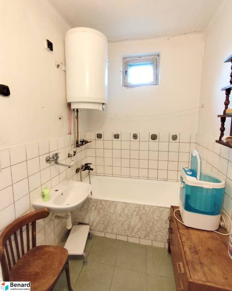 Bathroom in a family house with a bathtub, sink, washing machine, and water heater.