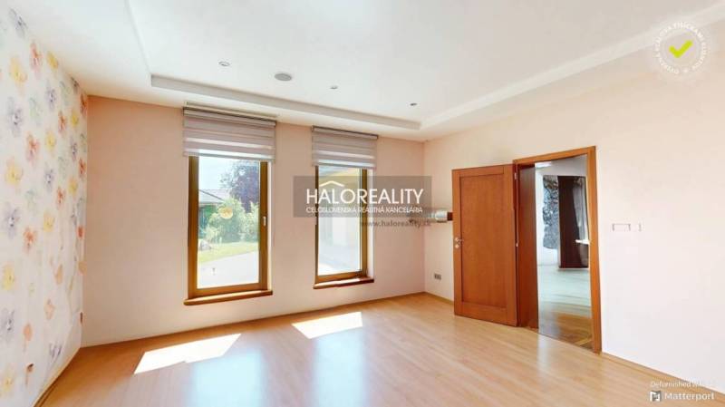 A bright room in a family house with wooden flooring and floral patterned wallpaper.